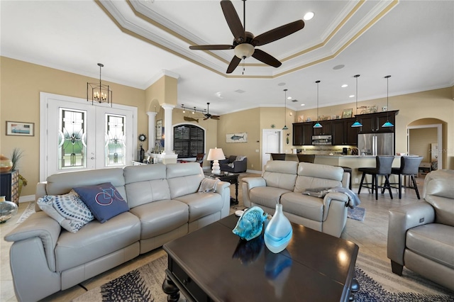 tiled living room with ceiling fan with notable chandelier, a raised ceiling, and crown molding