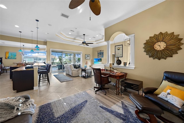 living room featuring ceiling fan, ornate columns, ornamental molding, light tile patterned floors, and a tray ceiling