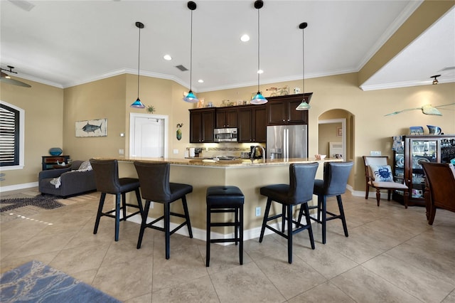 kitchen with a large island with sink, a kitchen breakfast bar, appliances with stainless steel finishes, decorative light fixtures, and dark brown cabinetry