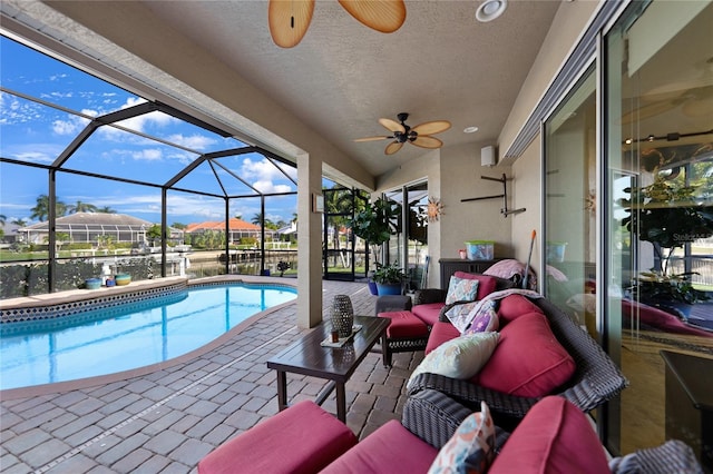 view of pool with outdoor lounge area, a patio area, ceiling fan, and glass enclosure