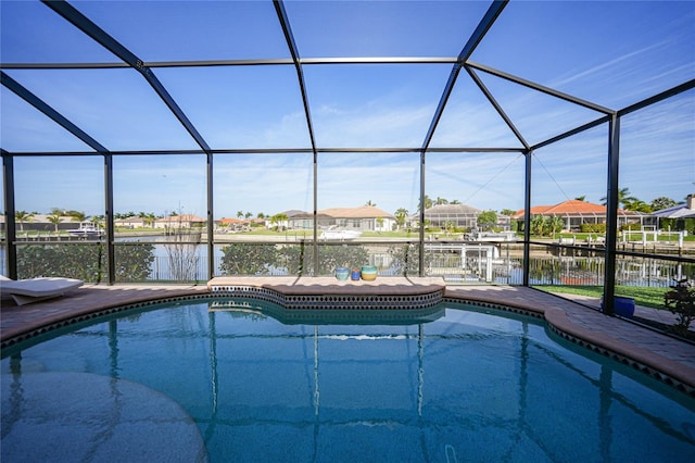 view of swimming pool with glass enclosure and a water view