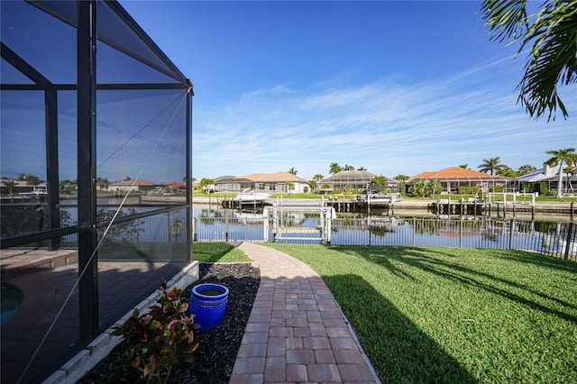 view of dock with a yard, a water view, and glass enclosure