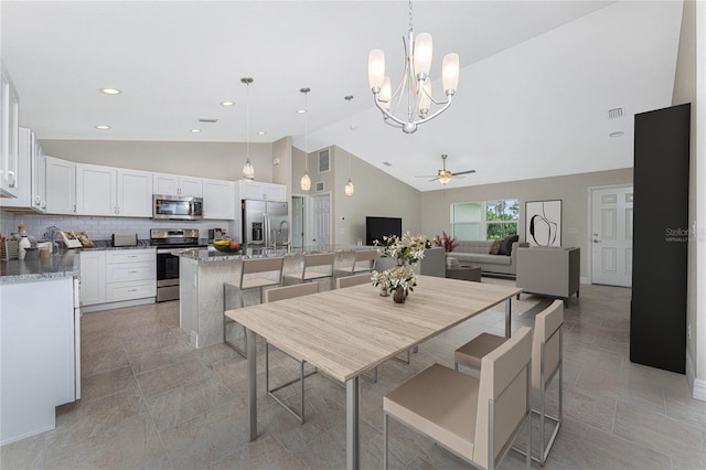 dining room featuring high vaulted ceiling and ceiling fan with notable chandelier