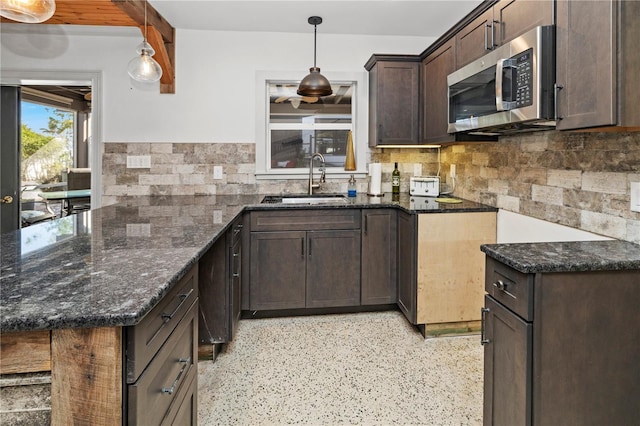 kitchen featuring dark brown cabinets, sink, dark stone counters, and decorative light fixtures