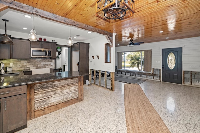 kitchen featuring wooden ceiling, sink, ceiling fan, dark stone countertops, and dark brown cabinets