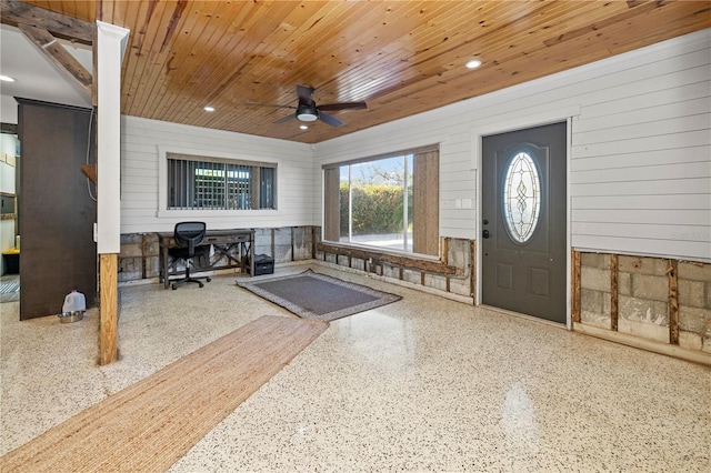 entrance foyer with ceiling fan, wooden ceiling, and wood walls