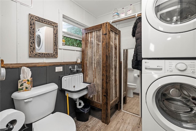 laundry room featuring stacked washer / dryer and light hardwood / wood-style floors