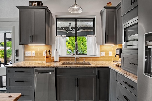 kitchen with decorative light fixtures, light stone counters, sink, and tasteful backsplash