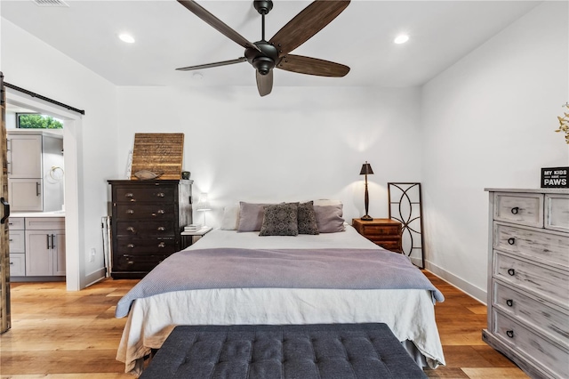 bedroom with light hardwood / wood-style floors, ensuite bath, and ceiling fan