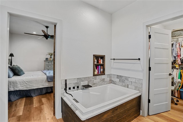 bathroom featuring wood-type flooring and a relaxing tiled tub