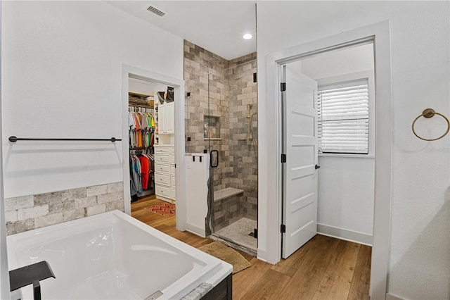 bathroom with independent shower and bath and wood-type flooring