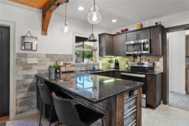 kitchen featuring dark stone counters, sink, a breakfast bar area, dark brown cabinets, and stainless steel appliances