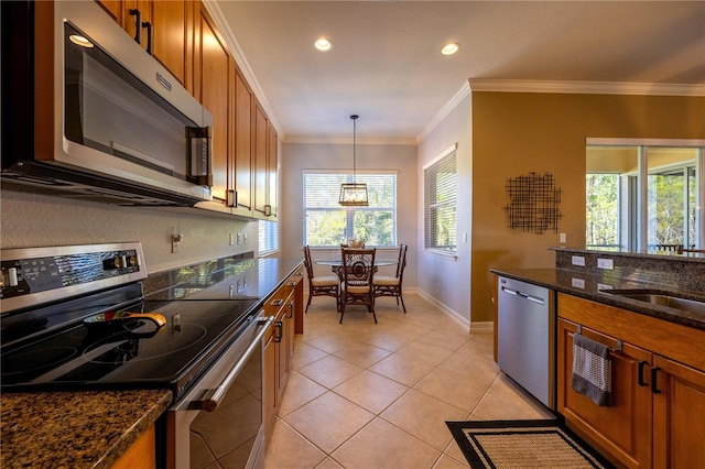 kitchen with crown molding, dark stone countertops, light tile patterned floors, appliances with stainless steel finishes, and decorative light fixtures