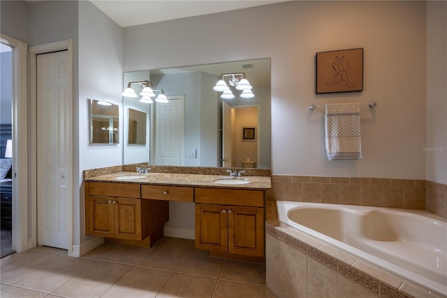 bathroom featuring tiled bath, tile patterned flooring, vanity, and a chandelier