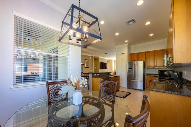 dining area with light tile patterned floors, ornamental molding, and a notable chandelier