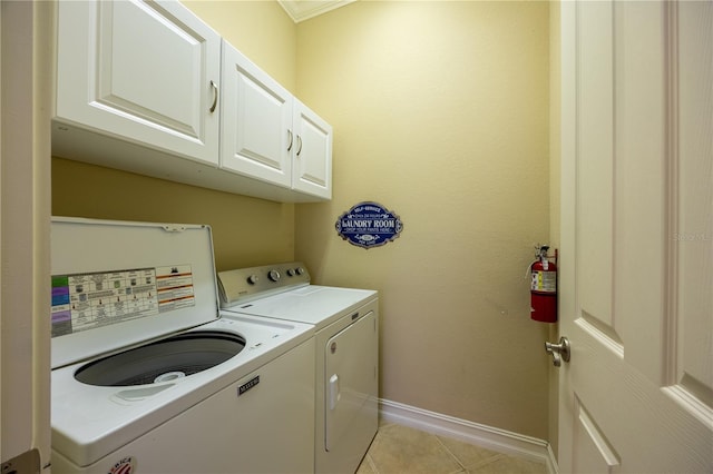 clothes washing area featuring cabinets, light tile patterned floors, washer and clothes dryer, and ornamental molding