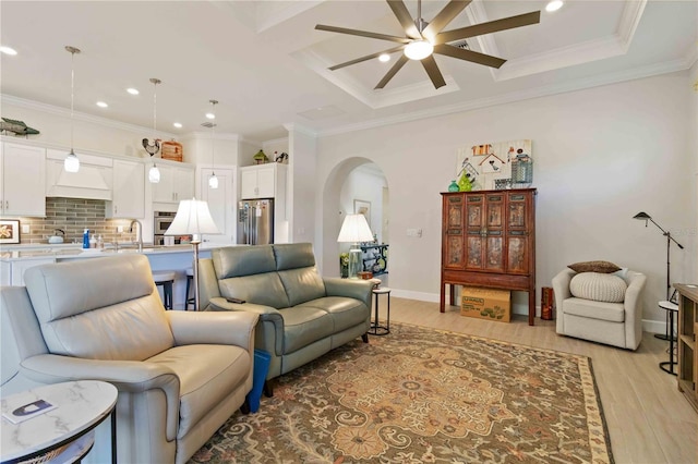 living room featuring ceiling fan, sink, ornamental molding, and light wood-type flooring