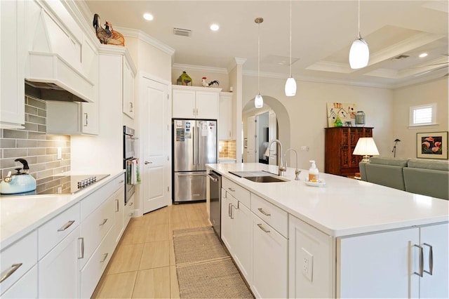 kitchen featuring pendant lighting, a center island with sink, sink, white cabinetry, and stainless steel appliances