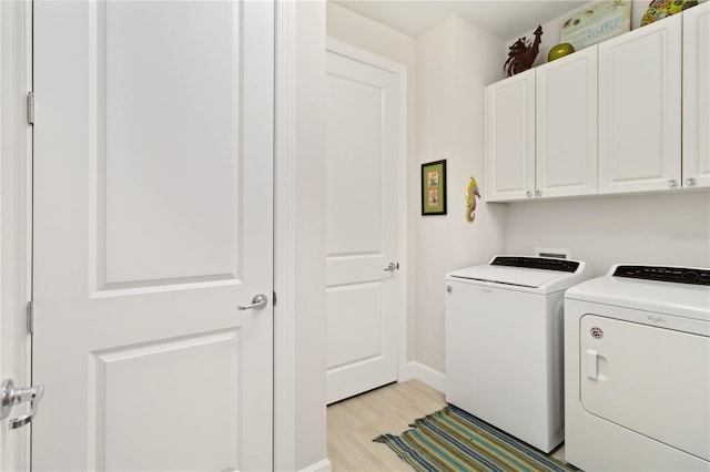 laundry room featuring cabinets, light wood-type flooring, and washer and clothes dryer