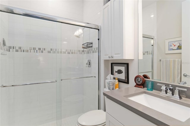 bathroom featuring vanity, a shower with shower door, and toilet