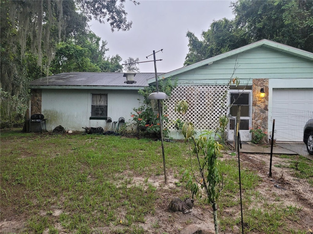 back of property featuring a garage and a lawn