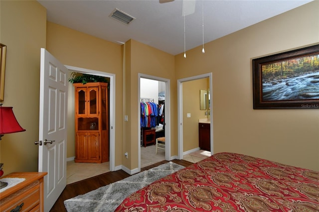 bedroom featuring light hardwood / wood-style flooring, ceiling fan, a spacious closet, connected bathroom, and a closet