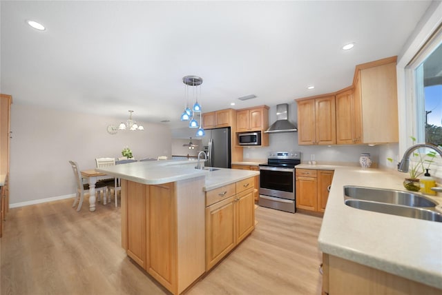 kitchen with a kitchen island with sink, sink, wall chimney exhaust hood, appliances with stainless steel finishes, and decorative light fixtures