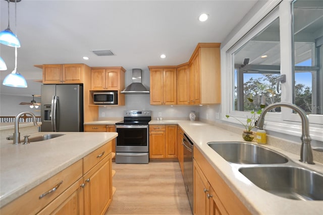 kitchen with decorative light fixtures, sink, stainless steel appliances, and wall chimney range hood