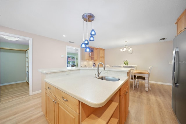 kitchen featuring a kitchen island with sink, sink, stainless steel fridge, light wood-type flooring, and light brown cabinetry