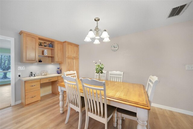 dining space with light wood-type flooring and an inviting chandelier