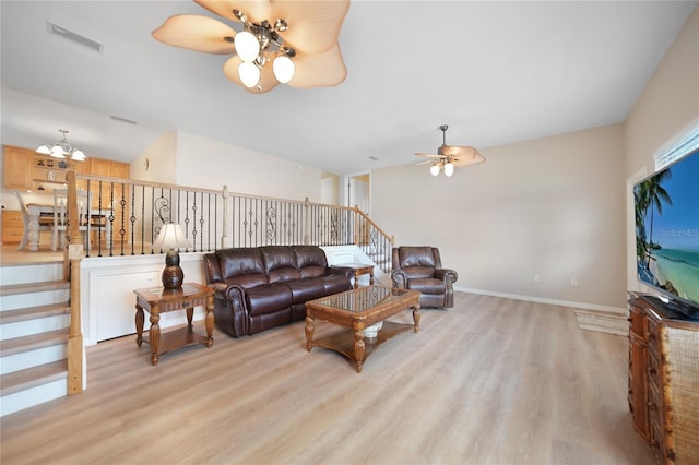 living room featuring ceiling fan with notable chandelier and light hardwood / wood-style flooring