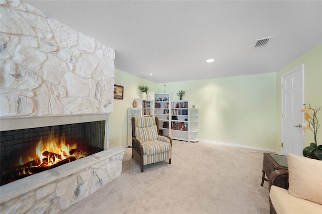 living area featuring a stone fireplace and light colored carpet