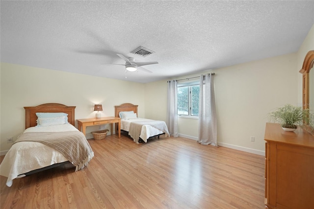 bedroom with ceiling fan, light hardwood / wood-style floors, and a textured ceiling