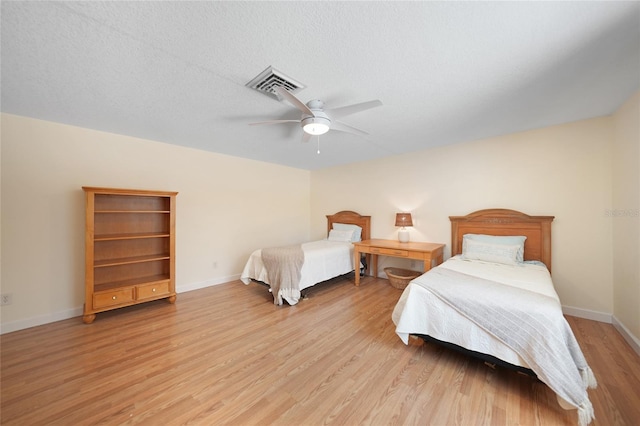 bedroom with ceiling fan, light wood-type flooring, and a textured ceiling