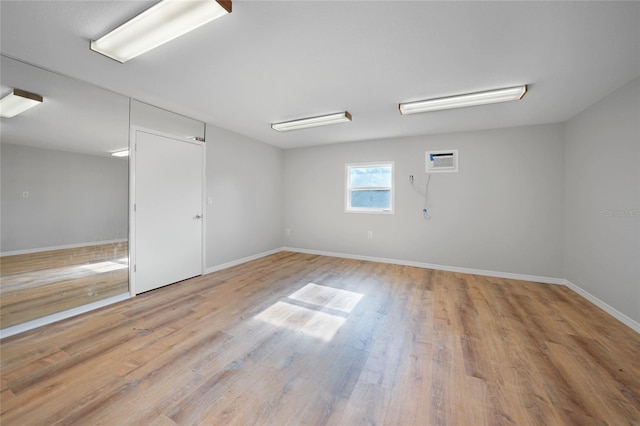 unfurnished room featuring an AC wall unit and light wood-type flooring