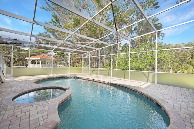 view of swimming pool featuring glass enclosure, an in ground hot tub, and a patio area