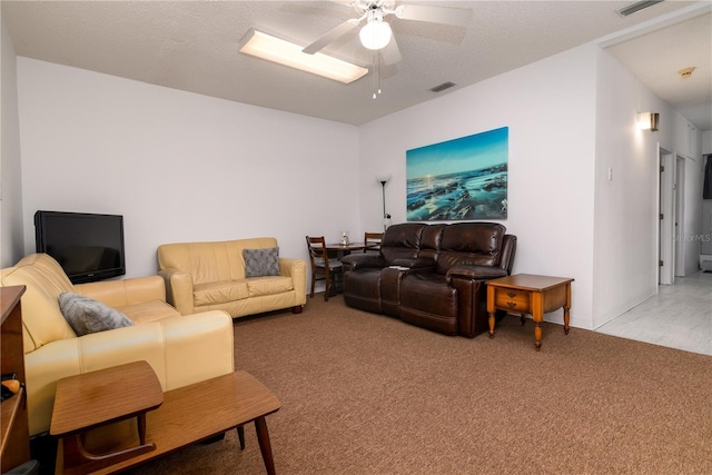 carpeted living room with ceiling fan and a textured ceiling