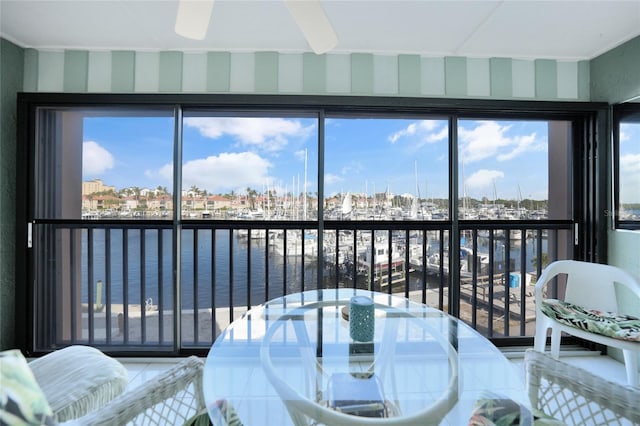 sunroom / solarium featuring a water view and ceiling fan