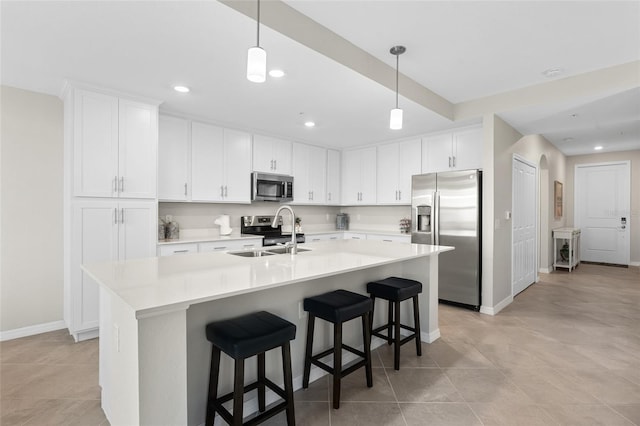 kitchen with pendant lighting, a center island with sink, white cabinets, sink, and appliances with stainless steel finishes