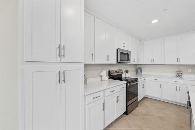 kitchen with white cabinets, appliances with stainless steel finishes, and light tile patterned floors