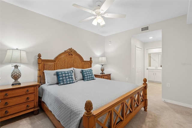 bedroom with connected bathroom, light colored carpet, and ceiling fan