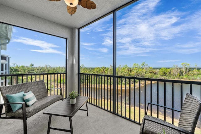 sunroom / solarium featuring ceiling fan and a water view