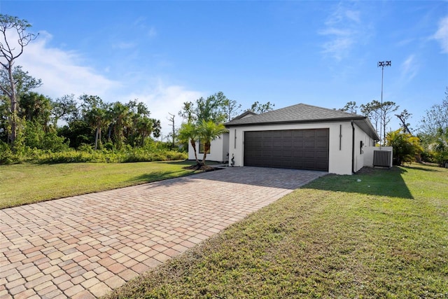 view of front of house with cooling unit, a garage, and a front lawn