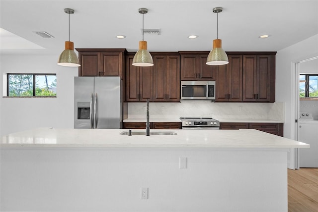 kitchen with pendant lighting, a wealth of natural light, sink, and stainless steel appliances