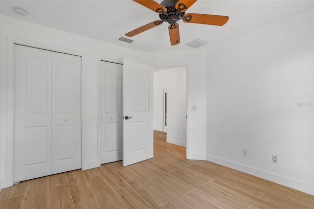 unfurnished bedroom featuring two closets, light hardwood / wood-style flooring, and ceiling fan