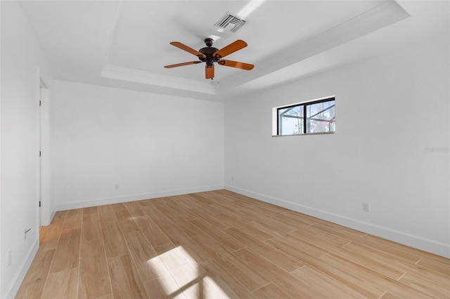 spare room with a tray ceiling, ceiling fan, and light hardwood / wood-style floors