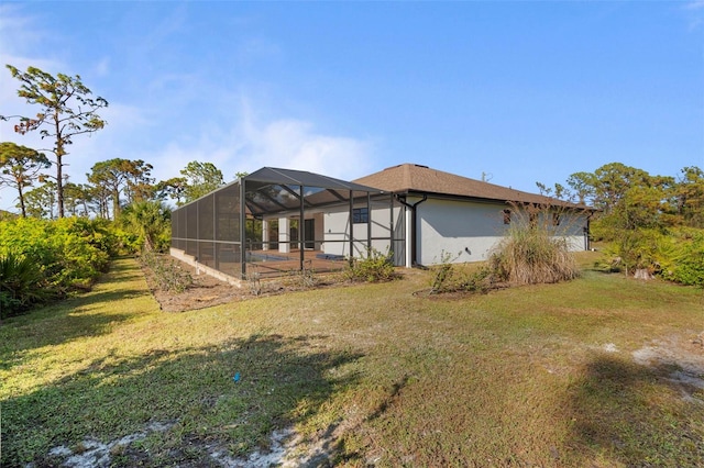 back of property featuring a lawn and glass enclosure