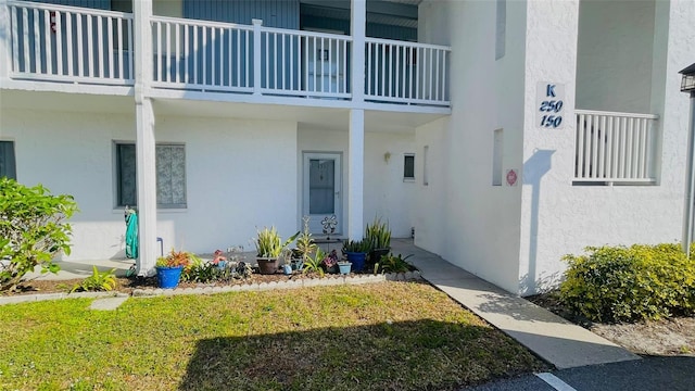 property entrance featuring a balcony and a lawn