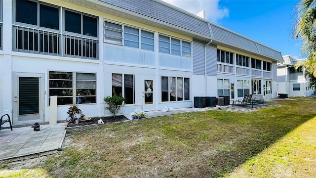 rear view of property featuring a yard, central AC, and a patio area