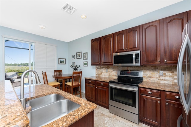 kitchen with decorative backsplash, sink, light stone countertops, and stainless steel appliances